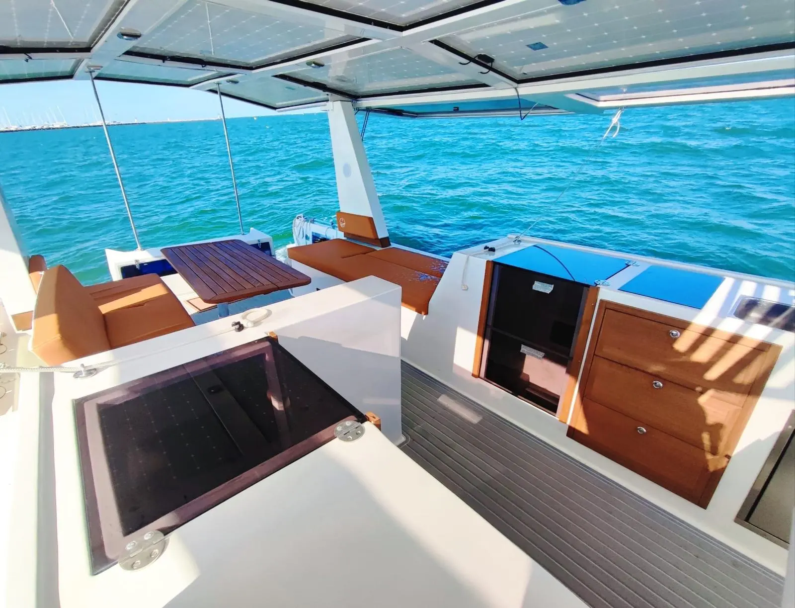 Millikan Boats M9 — Cockpit arrière d’un bateau avec banquettes, table et accès à la cabine.