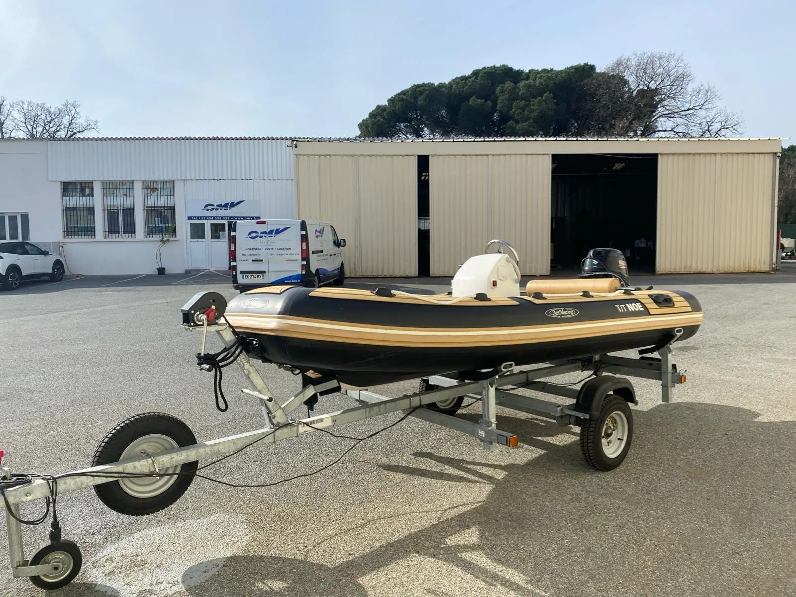 AER Marine Alusmart 350 — Bateau pneumatique noir et beige posé sur une remorque devant un hangar.