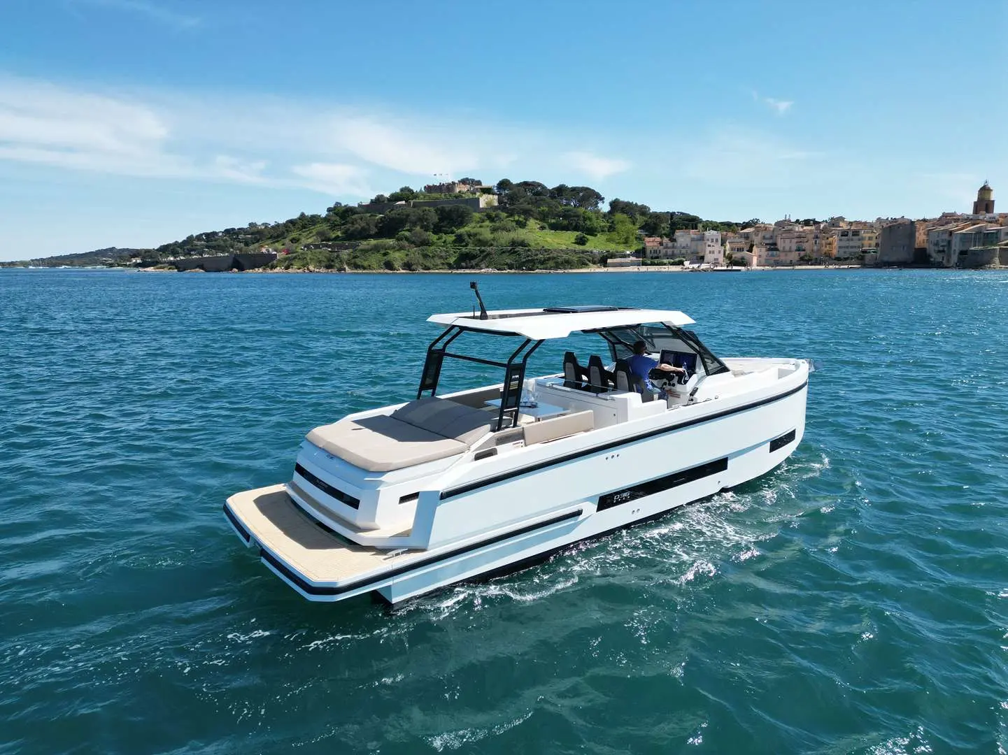 De Antonio Yachts D36 Hard Top — Bateau à moteur blanc naviguant devant une côte méditerranéenne.