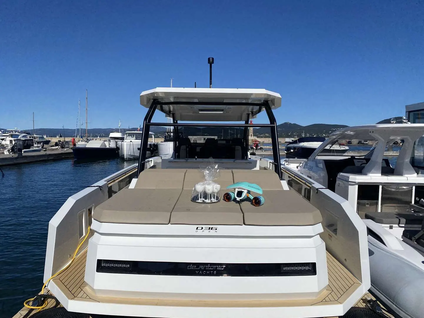 De Antonio Yachts D36 Hard Top — Vue du bain de soleil avant et du poste de pilotage d’un bateau au port.