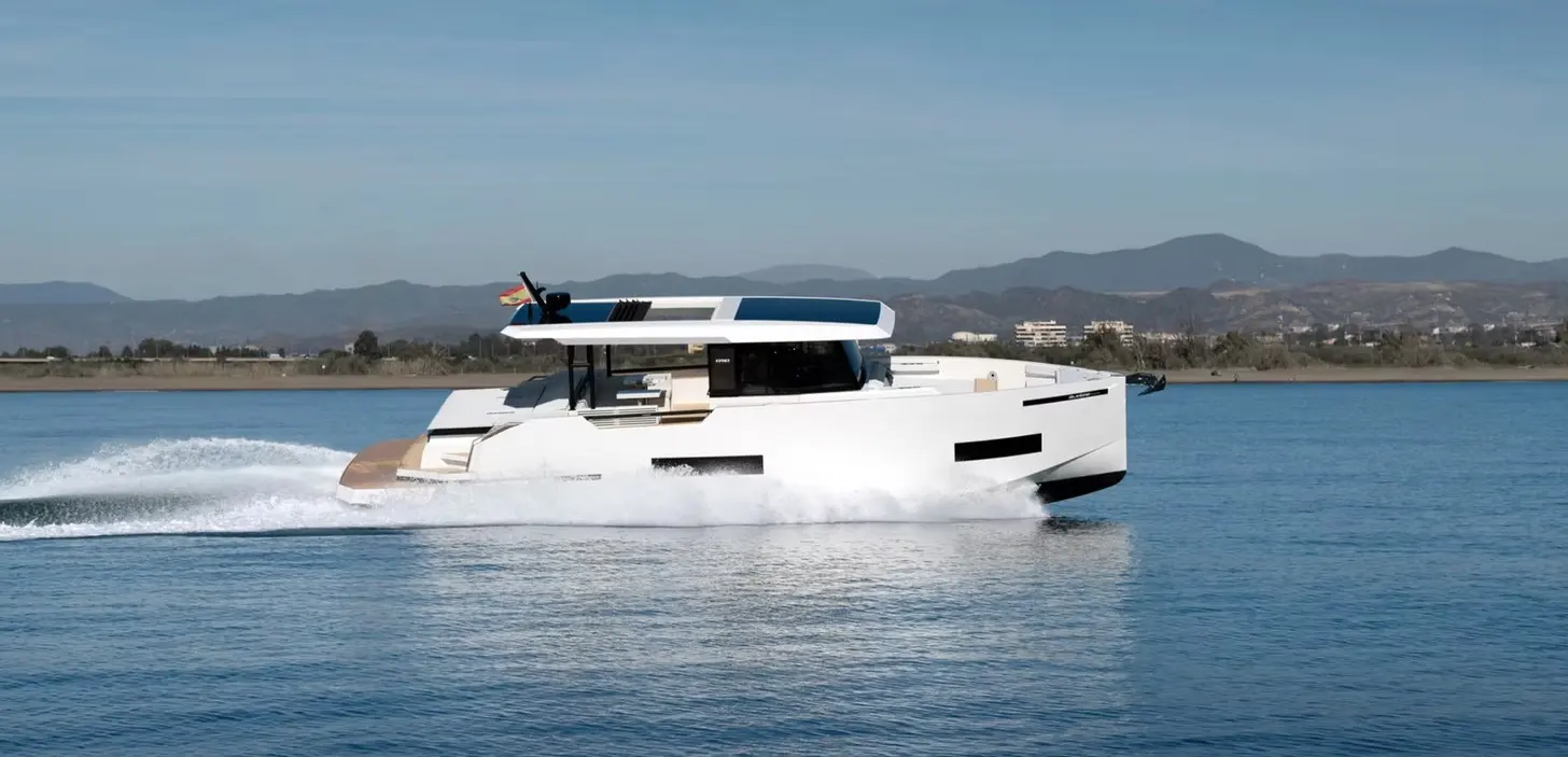 De Antonio Yachts D50 Coupe — Bateau à moteur blanc naviguant à vive allure sur une eau calme, vu de profil.