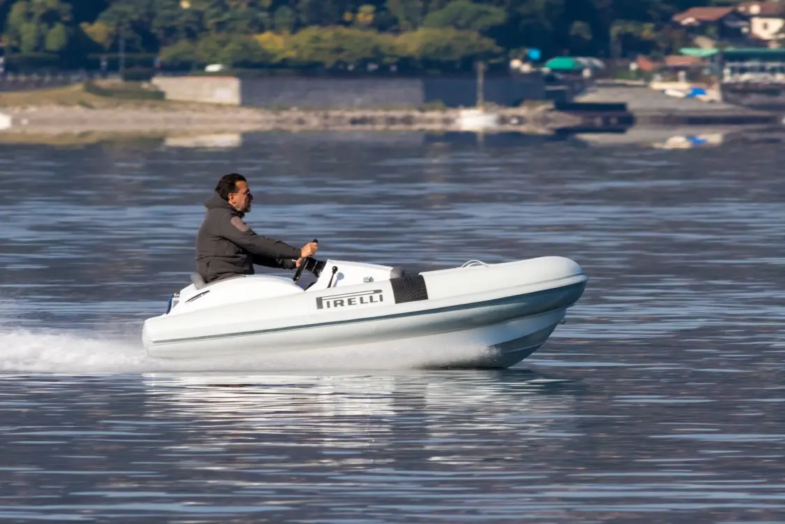Pirelli J29 — Bateau semi-rigide blanc naviguant sur l’eau avec un pilote à la barre.