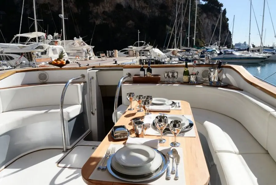 Monte Carlo Cigarette — Cockpit arrière aménagé avec table dressée et banquettes, dans un port.