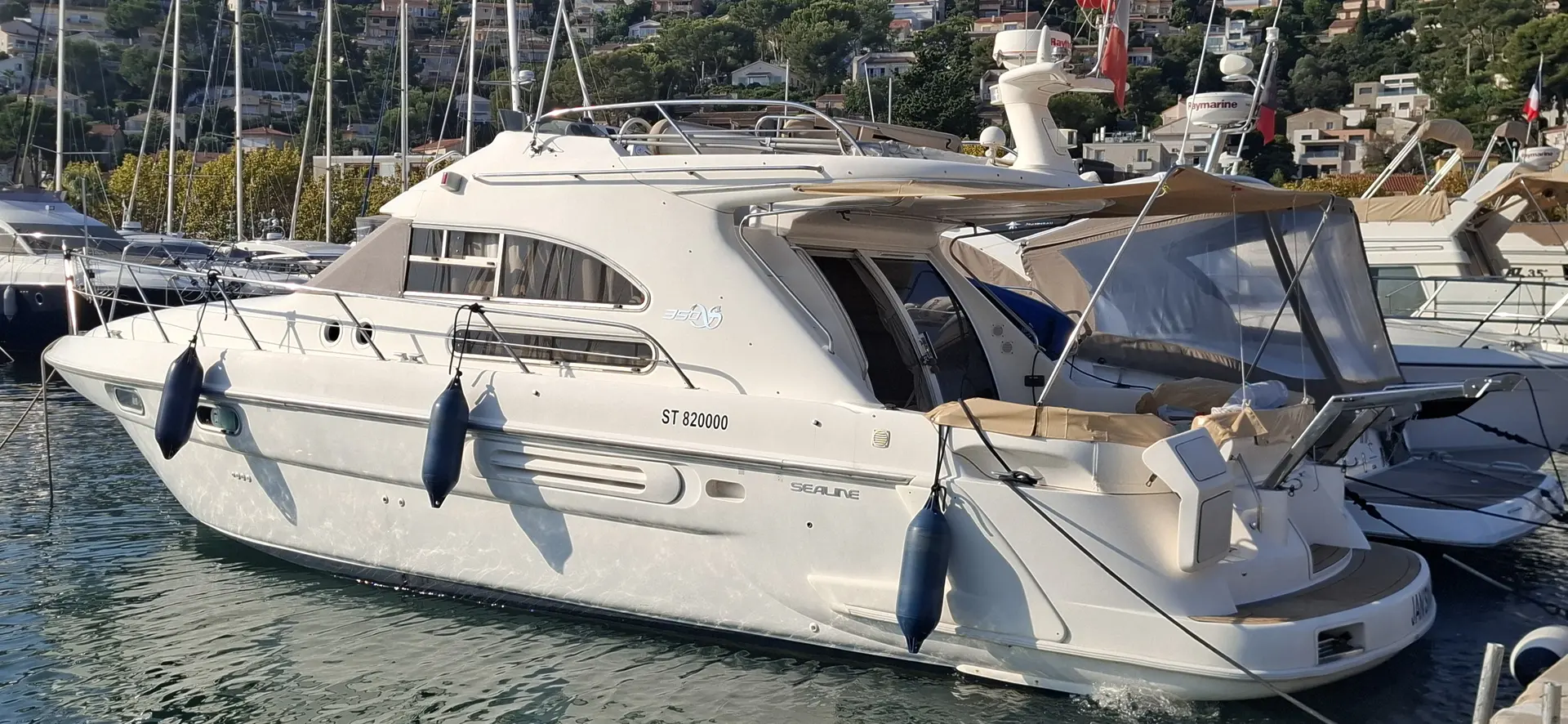 Sealine 350 Fly — Bateau à moteur blanc vu de trois-quarts arrière dans une marina.