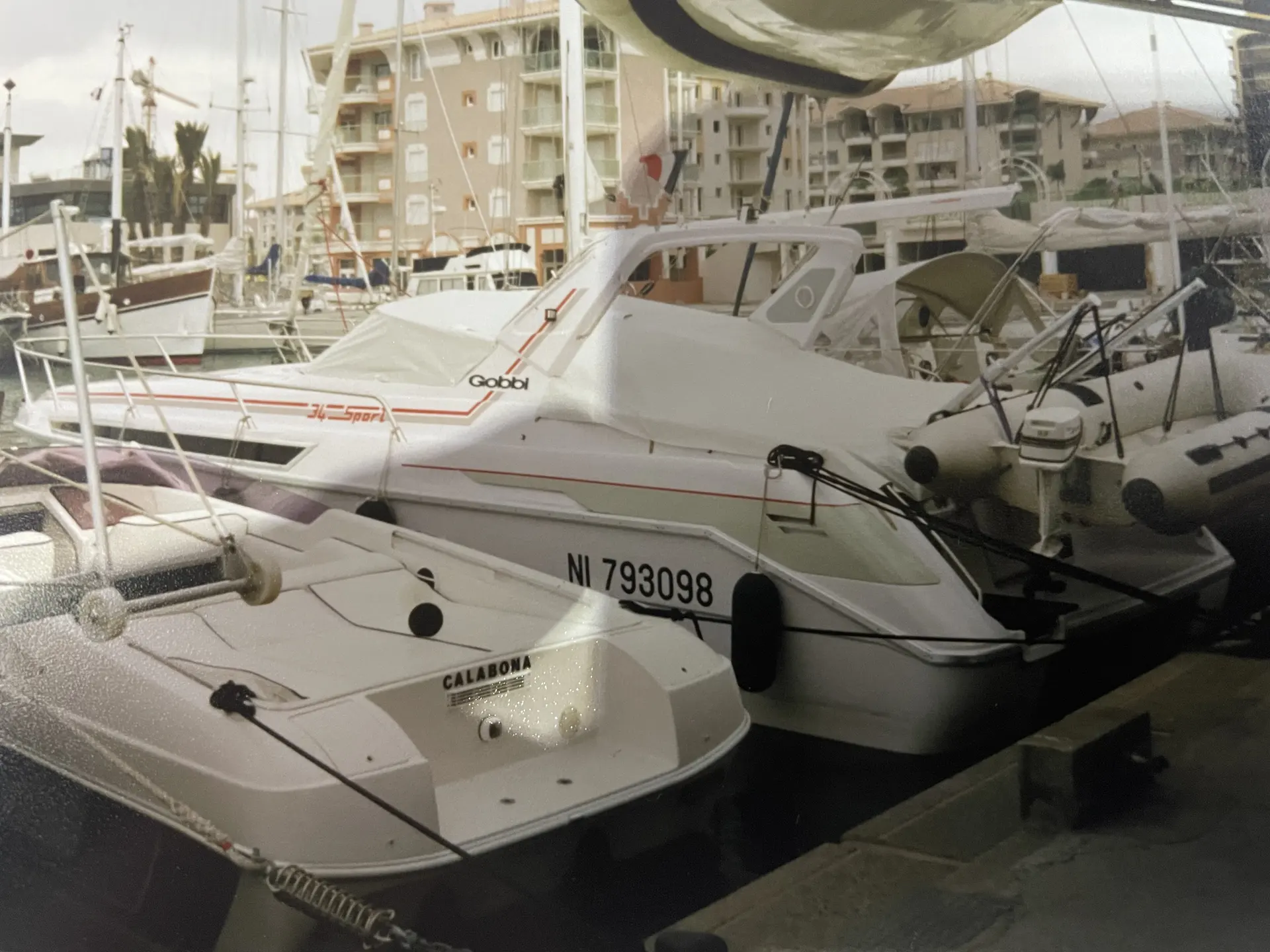 Gobbi 34 Sport — Bateau à moteur blanc amarré dans une marina, partiellement masqué par d'autres embarcations.