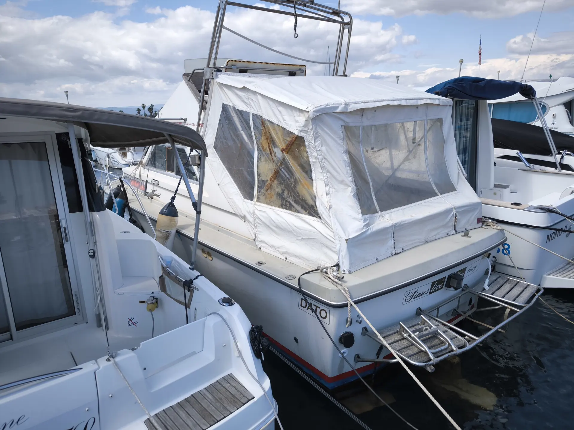 Coronet 24 — Bateau à moteur amarré, vu de trois quarts arrière, avec taud de cockpit.