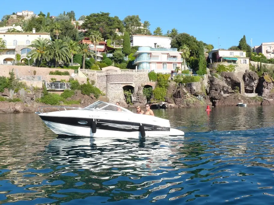 Bayliner 642 CU — Bateau à moteur noir et blanc naviguant devant une côte résidentielle.