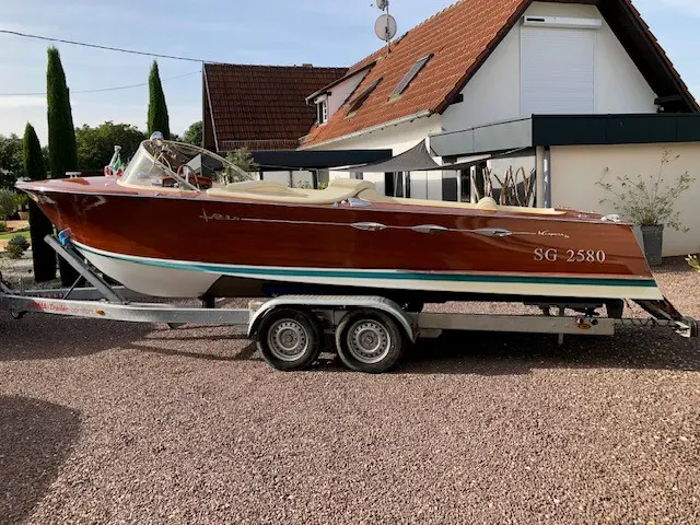 Rio Espera — Bateau à moteur présenté de profil sur une remorque devant une maison.