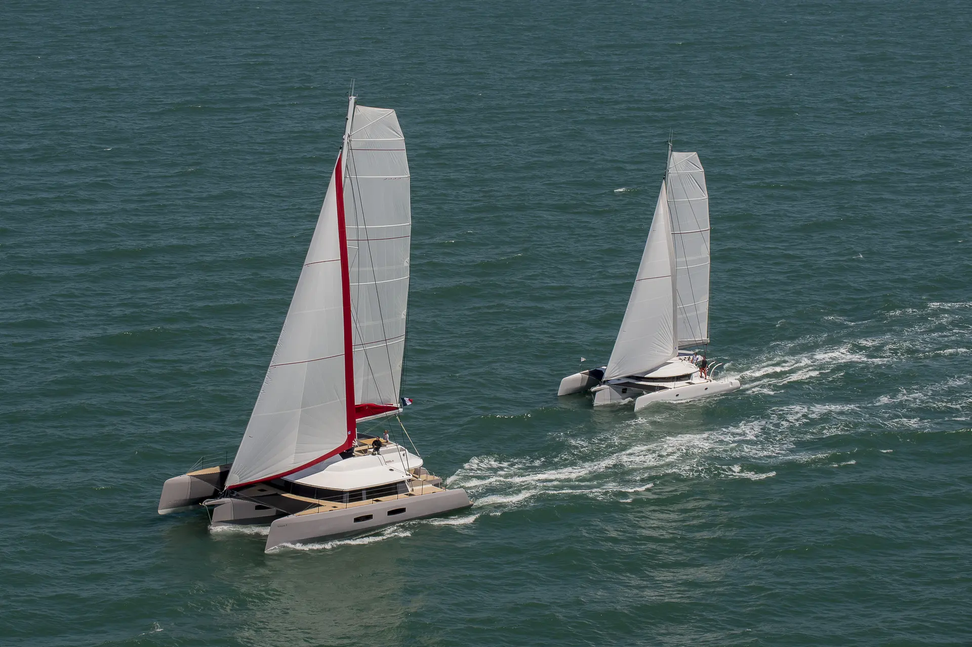 Neel Trimarans Neel 65 — Deux trimarans naviguent à la voile sur une mer agitée.
