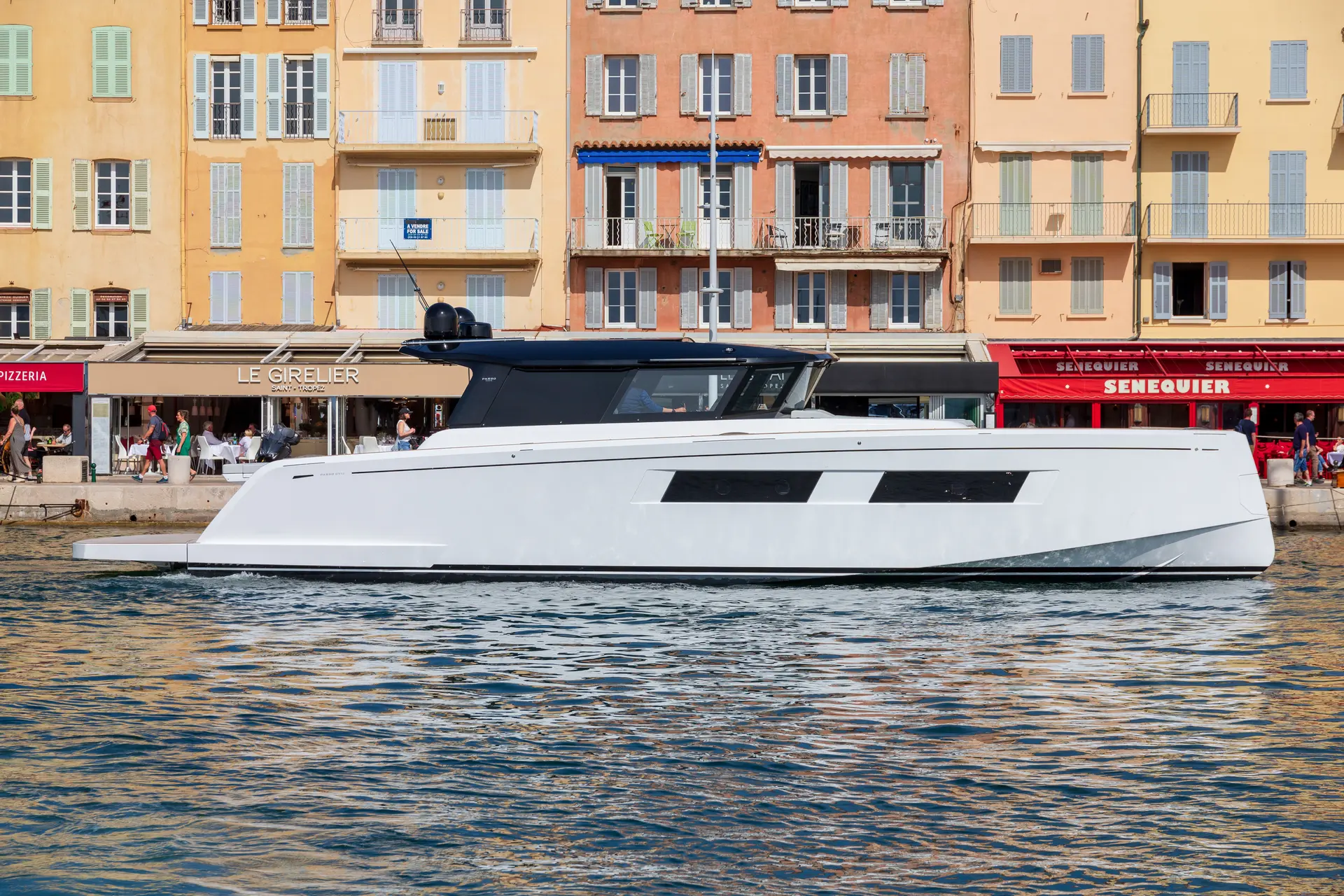 Pardo Yachts Pardo 52 GT — Vue de profil d’un bateau blanc et noir naviguant devant des façades colorées.