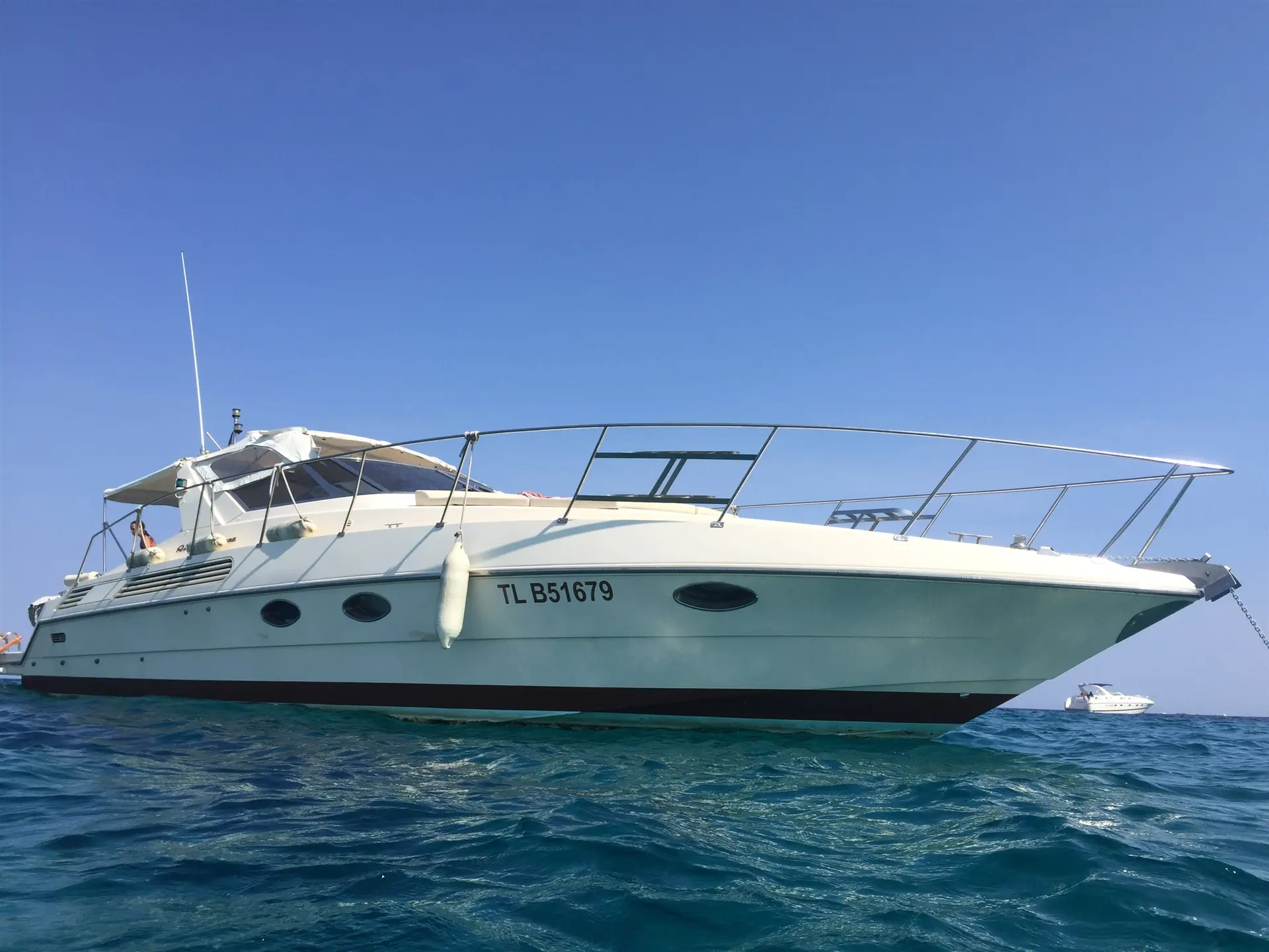 Riva Tropicana 43 — Bateau à moteur blanc vu de trois quarts depuis la surface de l’eau.