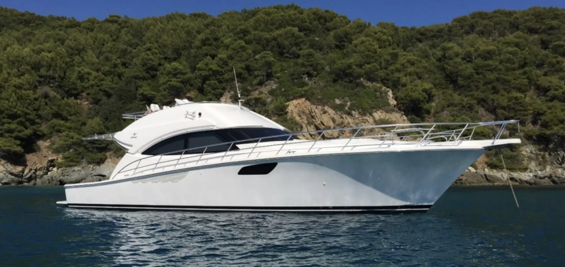 Bertram 540 — Bateau à moteur blanc vu de profil dans une crique boisée.