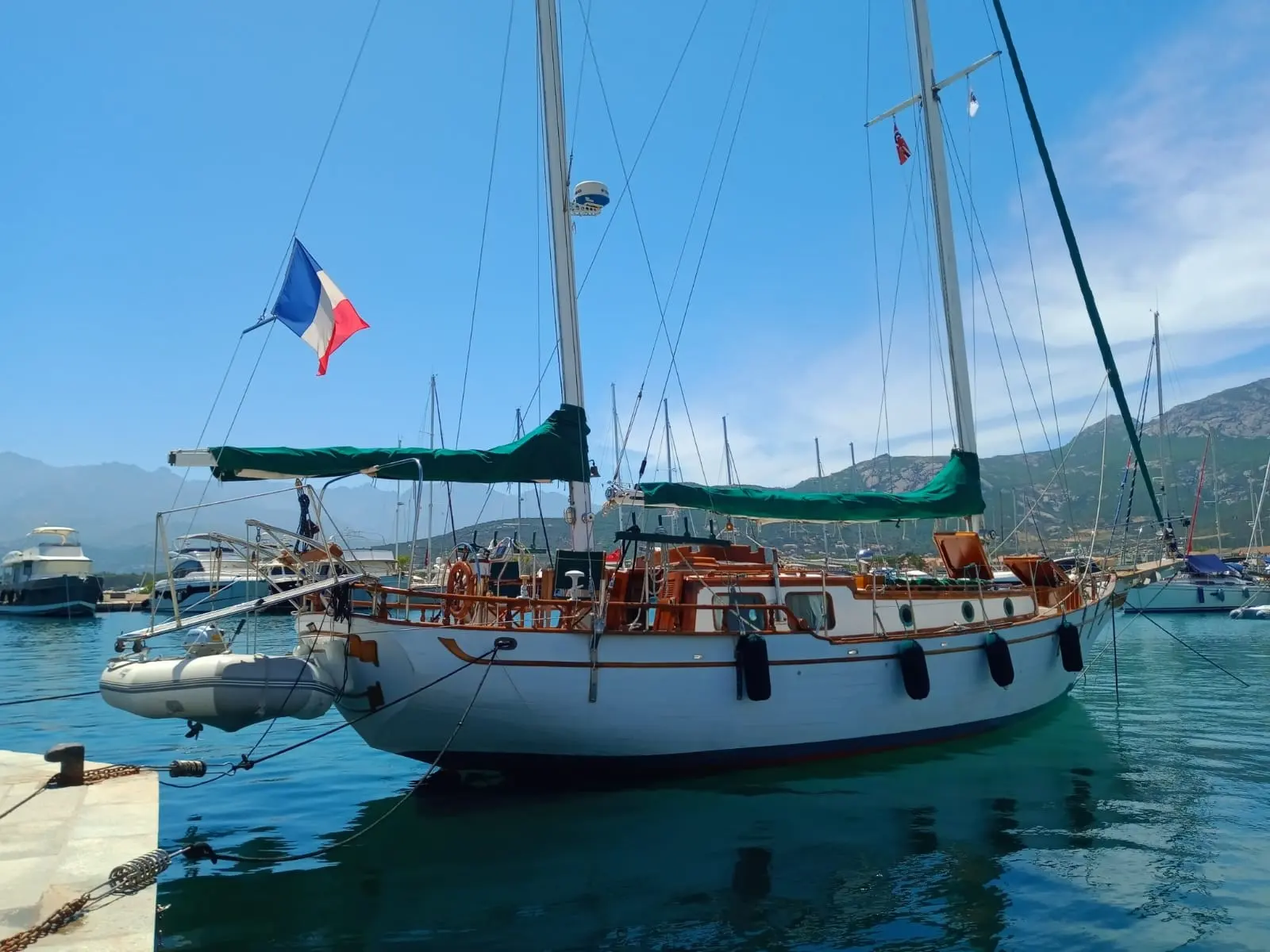 Transworld TW41 — Voilier amarré dans un port, avec annexe et montagnes en arrière-plan.