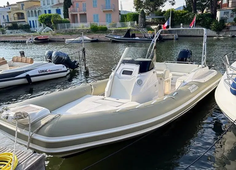 Joker Boat Clubman — Bateau pneumatique gris amarré, vu de trois quarts dans un port.