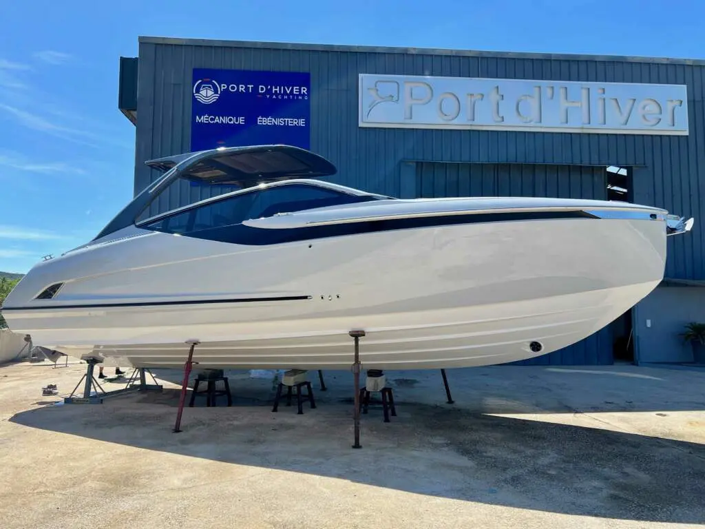 Fairline F-Line 33 — Bateau à moteur blanc photographié à sec devant un chantier nautique.