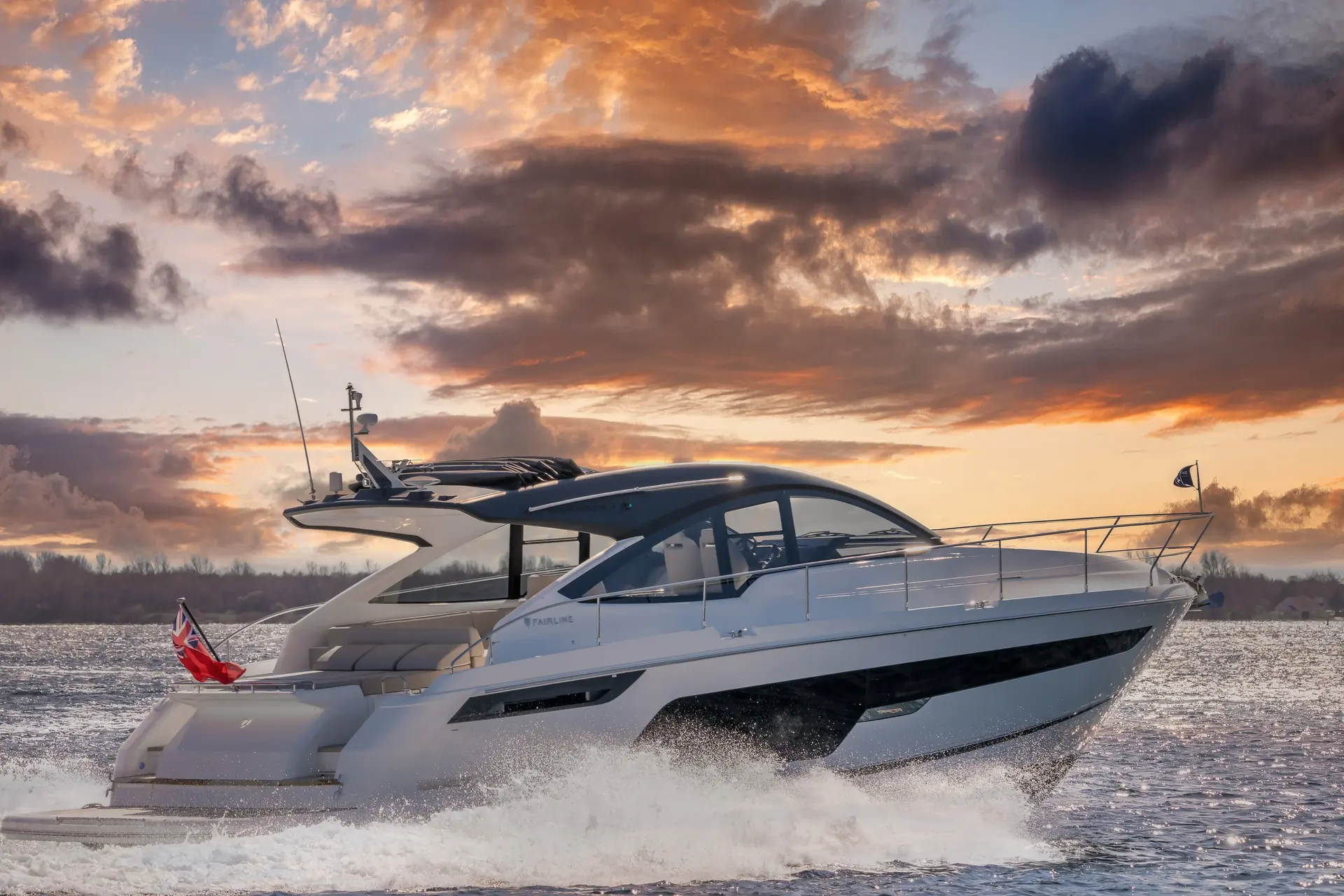 Fairline Targa 50 Open — Bateau à moteur blanc naviguant sur une rivière au coucher du soleil.