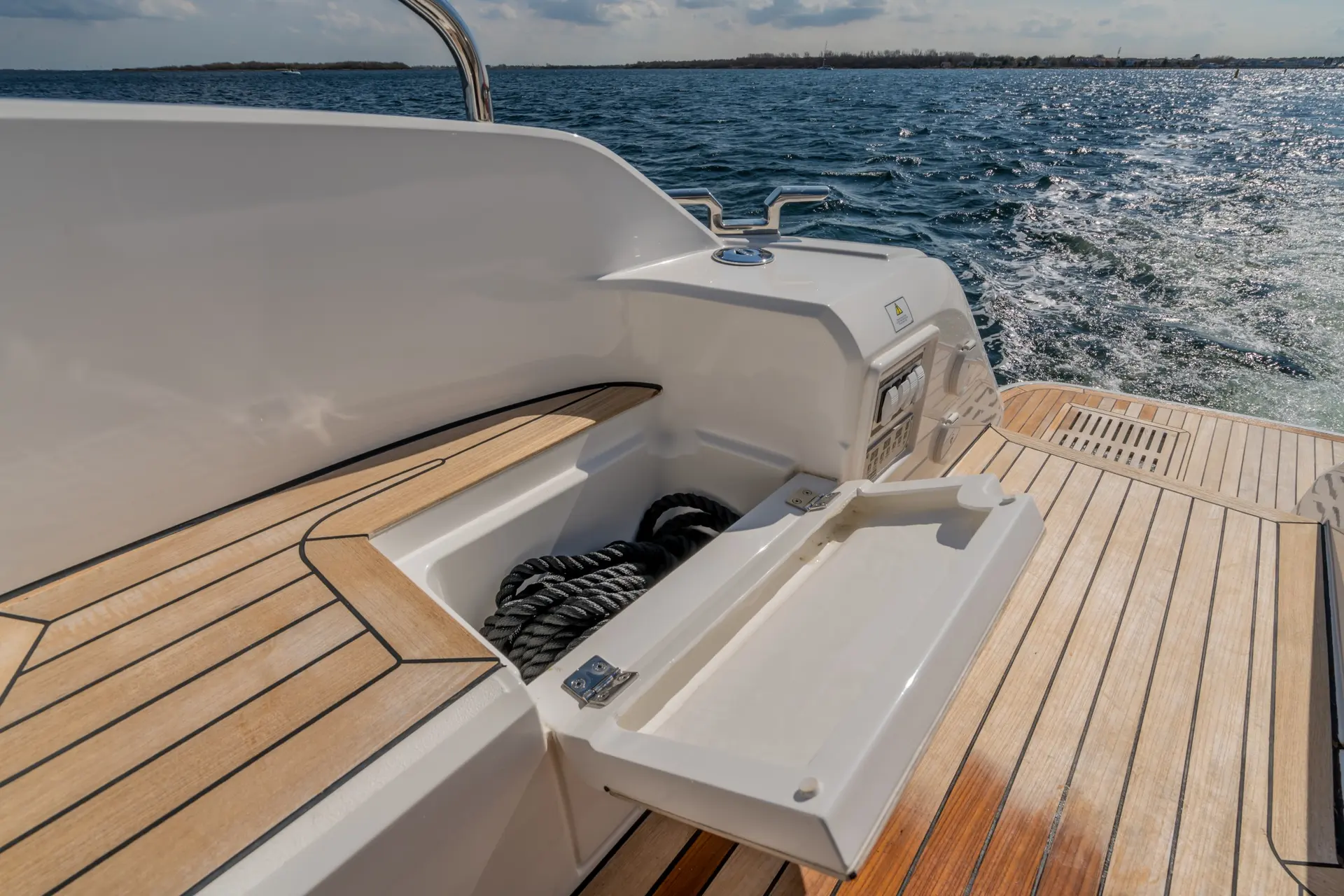 Fairline Targa 50 Open — Vue rapprochée de la plateforme arrière en teck, avec cordage et mer en arrière-plan.