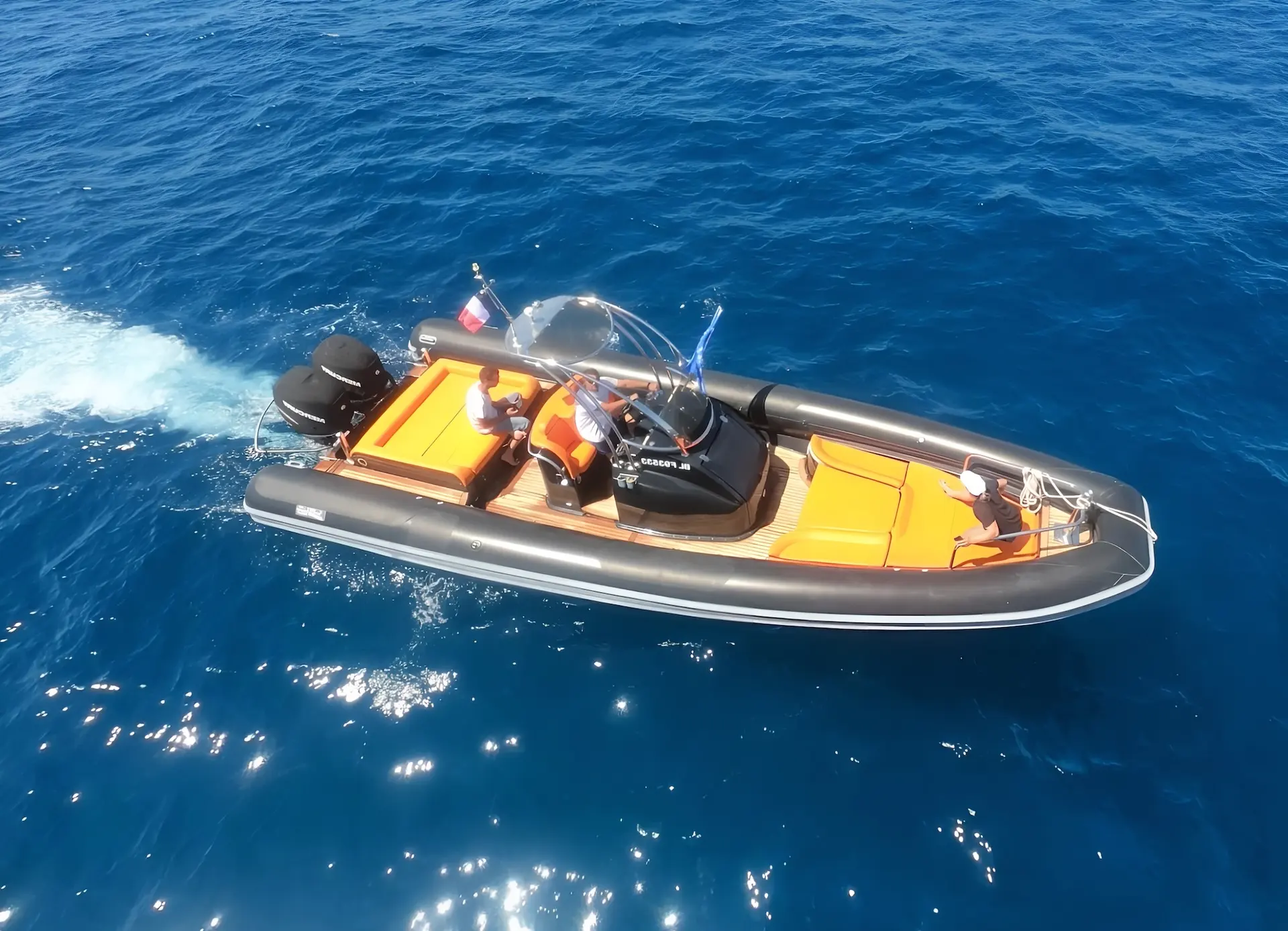 Sea Water Smeralda 320 — Bateau semi-rigide vu du dessus, naviguant sur une mer bleue avec trois personnes à bord.