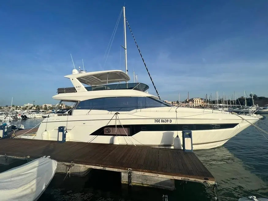 Prestige Yachts 630 Fly — Yacht blanc vu de profil, amarré dans un port de plaisance.