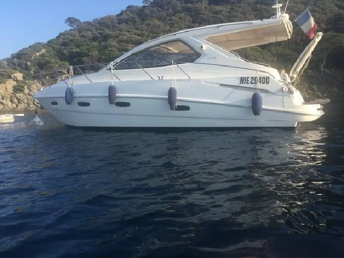 Sealine SC 38 — Bateau à moteur blanc vu de profil dans une baie, avec des défenses latérales.