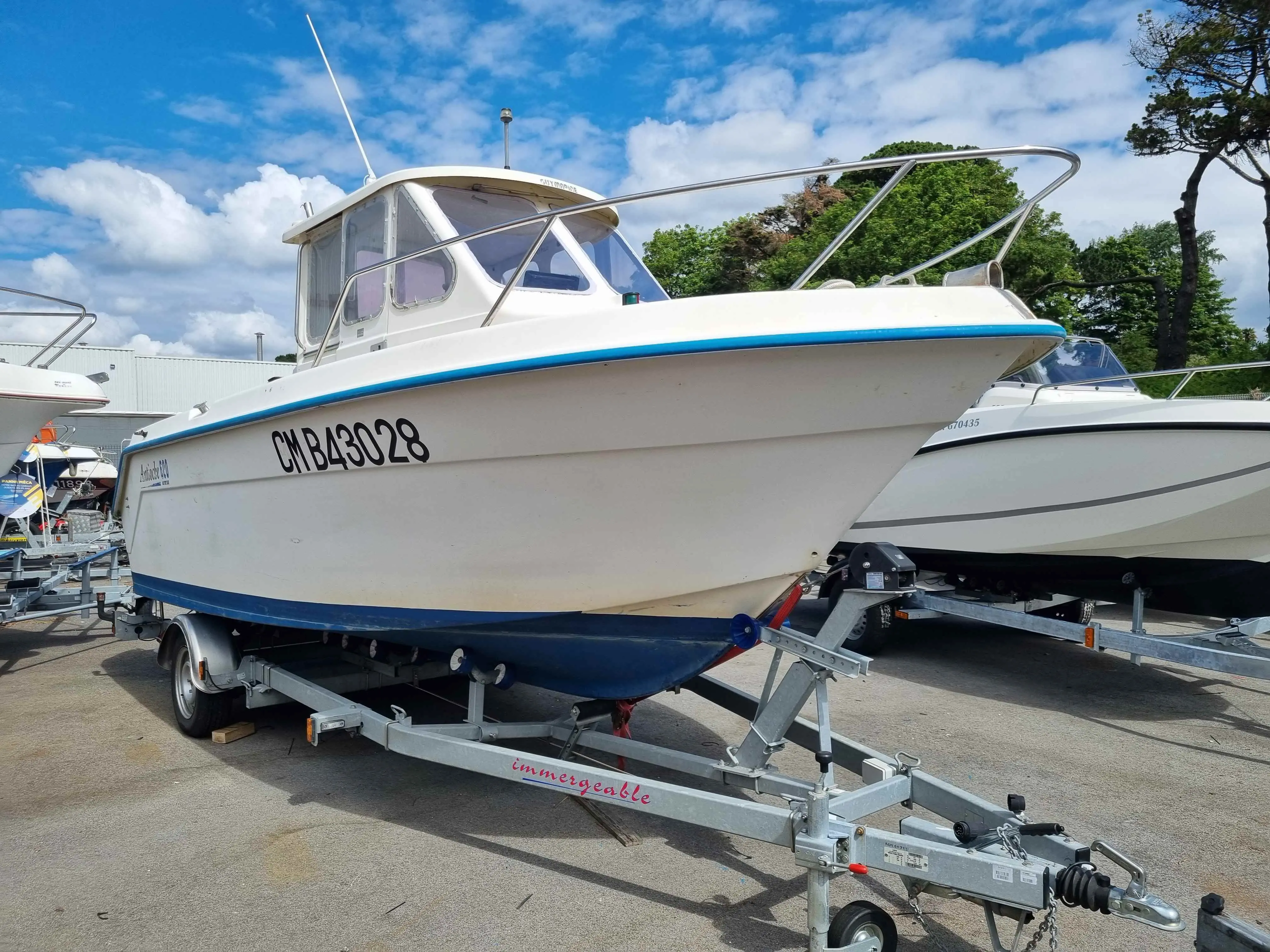 Guymarine Antioche 600 — Bateau à cabine blanche et liseré bleu présenté sur sa remorque dans un port à sec.