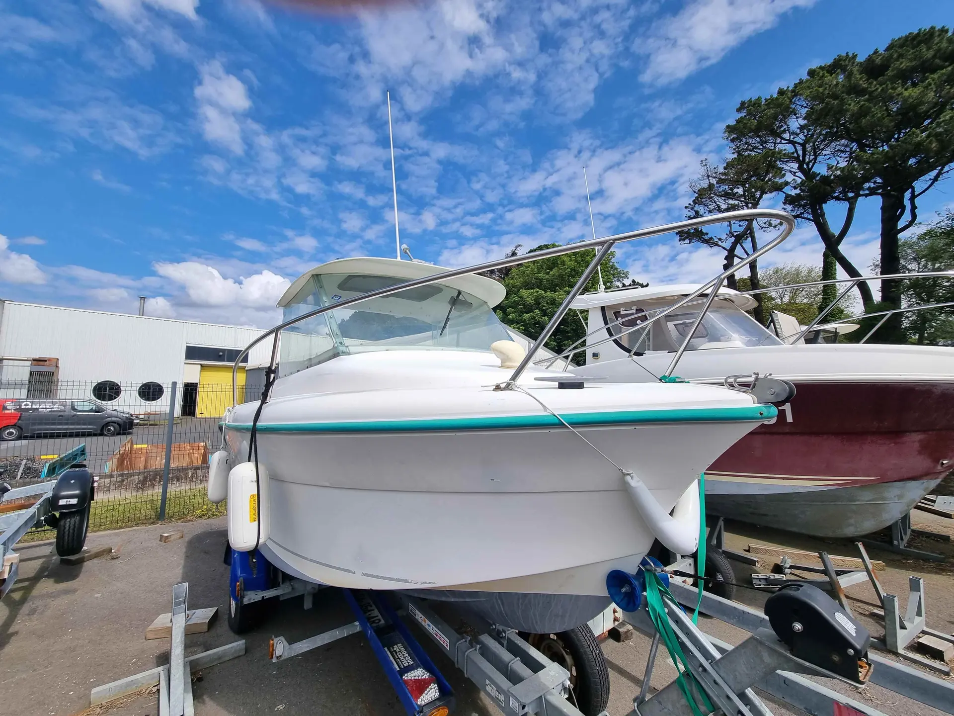 Ocqueteau 485 — Bateau à moteur blanc photographié sur sa remorque dans un chantier nautique.