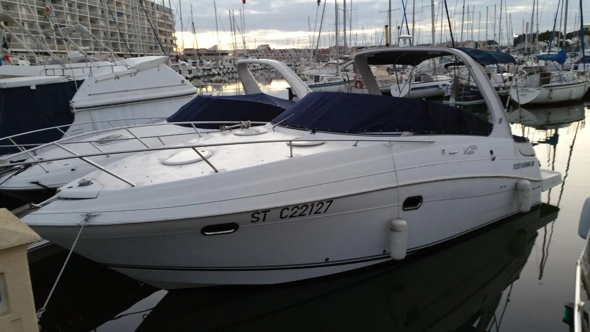 Four Winns V 288 — Bateau à moteur blanc amarré dans une marina, vu de trois quarts bâbord.