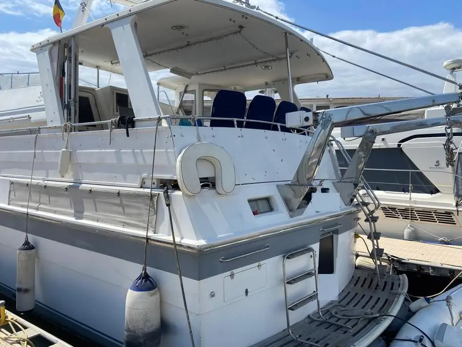 Hi Star 48 Motor Yacht — Vue arrière tribord d’un bateau blanc amarré, avec cockpit couvert et pare-battages.