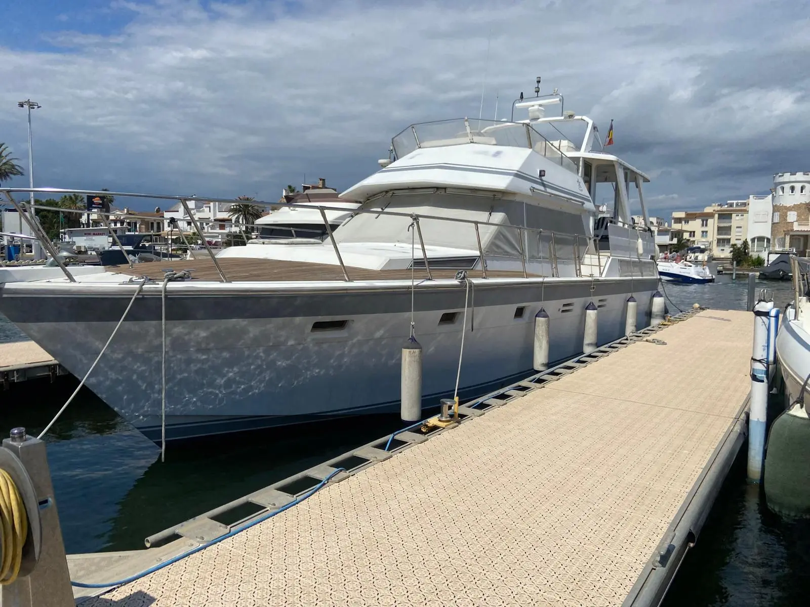 Hi Star 48 Motor Yacht — Bateau à moteur blanc et gris amarré dans une marina, vu de trois quarts avant.