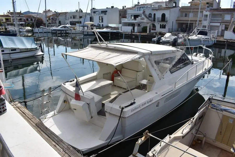 Gallart 1050 — Bateau à moteur blanc amarré dans un port, vu de trois quarts arrière.
