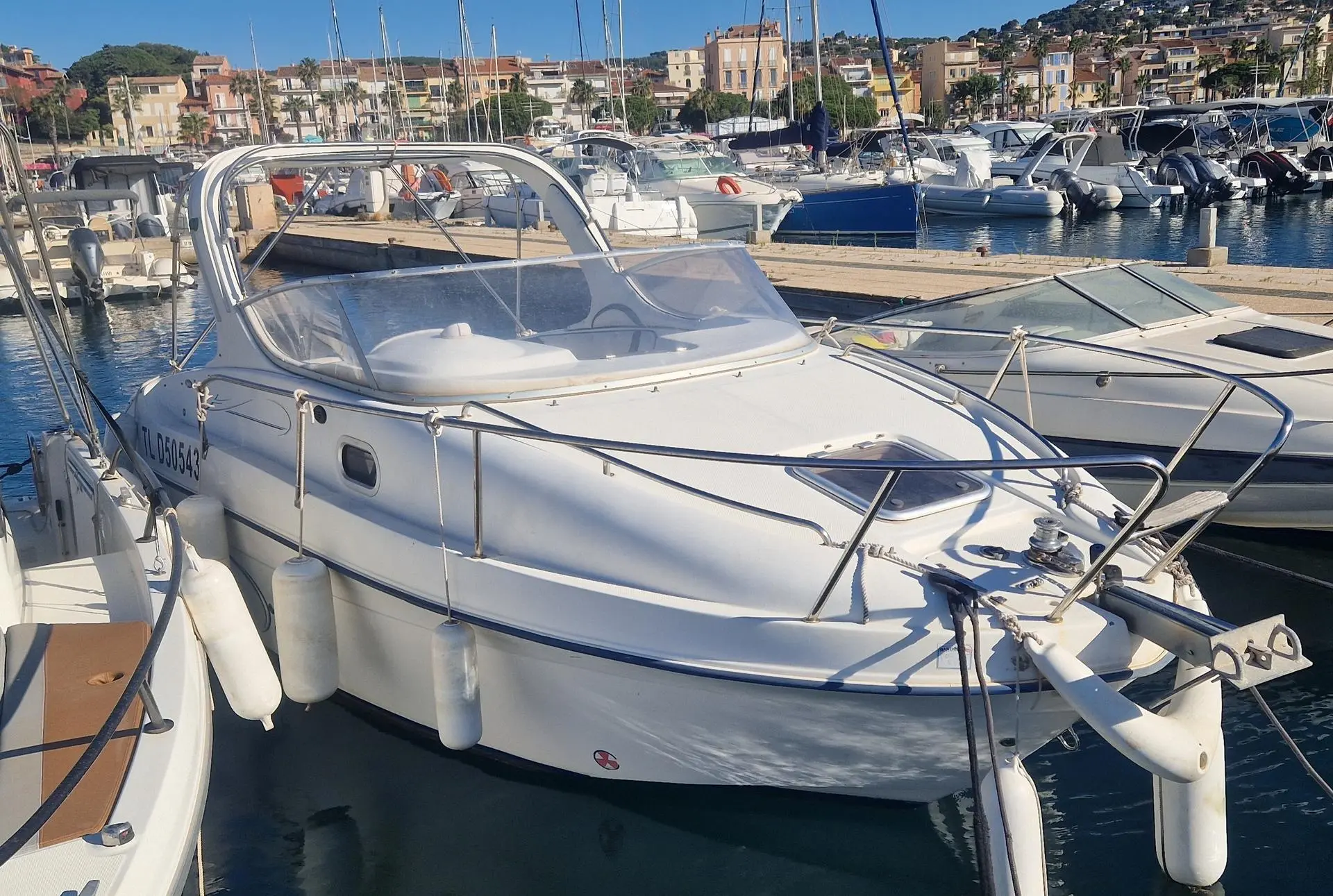 Saver 650 Cabine — Bateau à moteur blanc amarré dans une marina, vu de trois quarts avant.