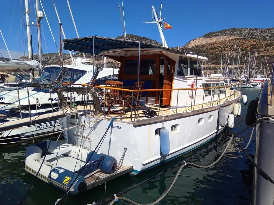 Dagless Fleur De Lys — Bateau à moteur blanc amarré dans une marina, vu de trois quarts arrière.