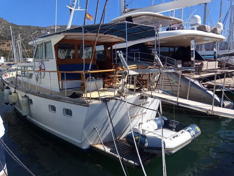 Dagless Fleur De Lys — Bateau à moteur blanc amarré dans une marina, avec annexe sur la plateforme arrière.
