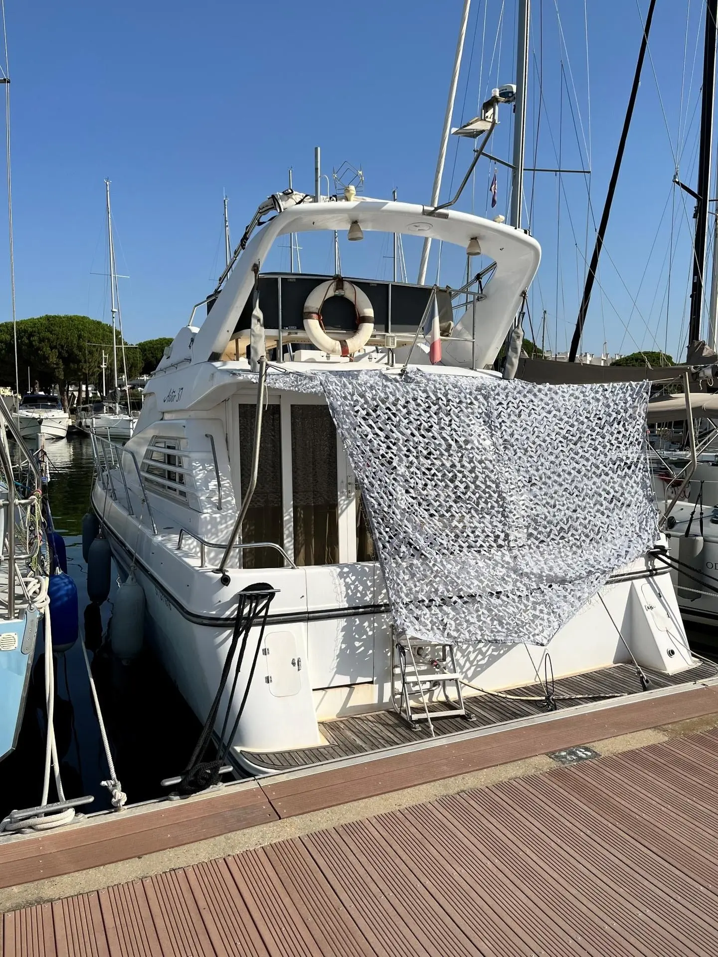 Astor 37 — Vue arrière d’un bateau amarré, avec une protection en filet couvrant le cockpit.