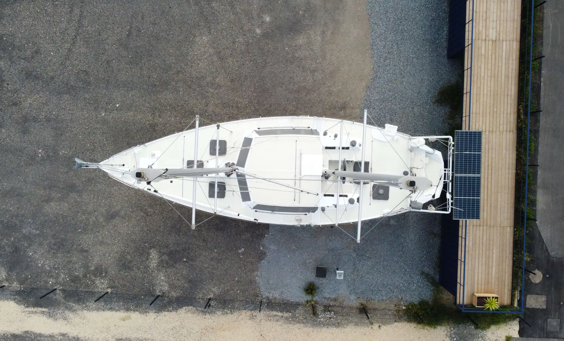 Alesia Marine Goelette 50 — Vue aérienne d’un voilier blanc stationné à terre, avec ses mâts et panneaux solaires.