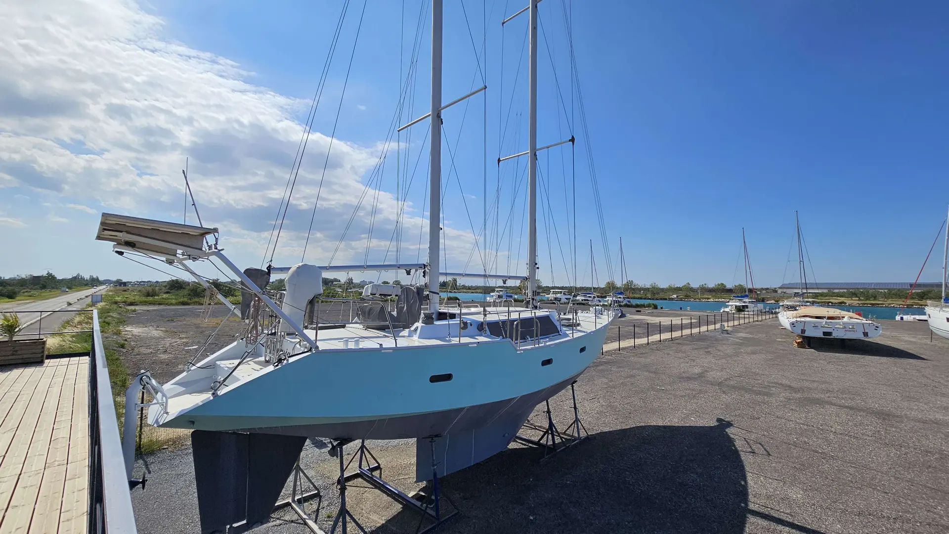 Alesia Marine Goelette 50 — Voilier bleu et blanc présenté à terre sur bers, au bord d’un port.