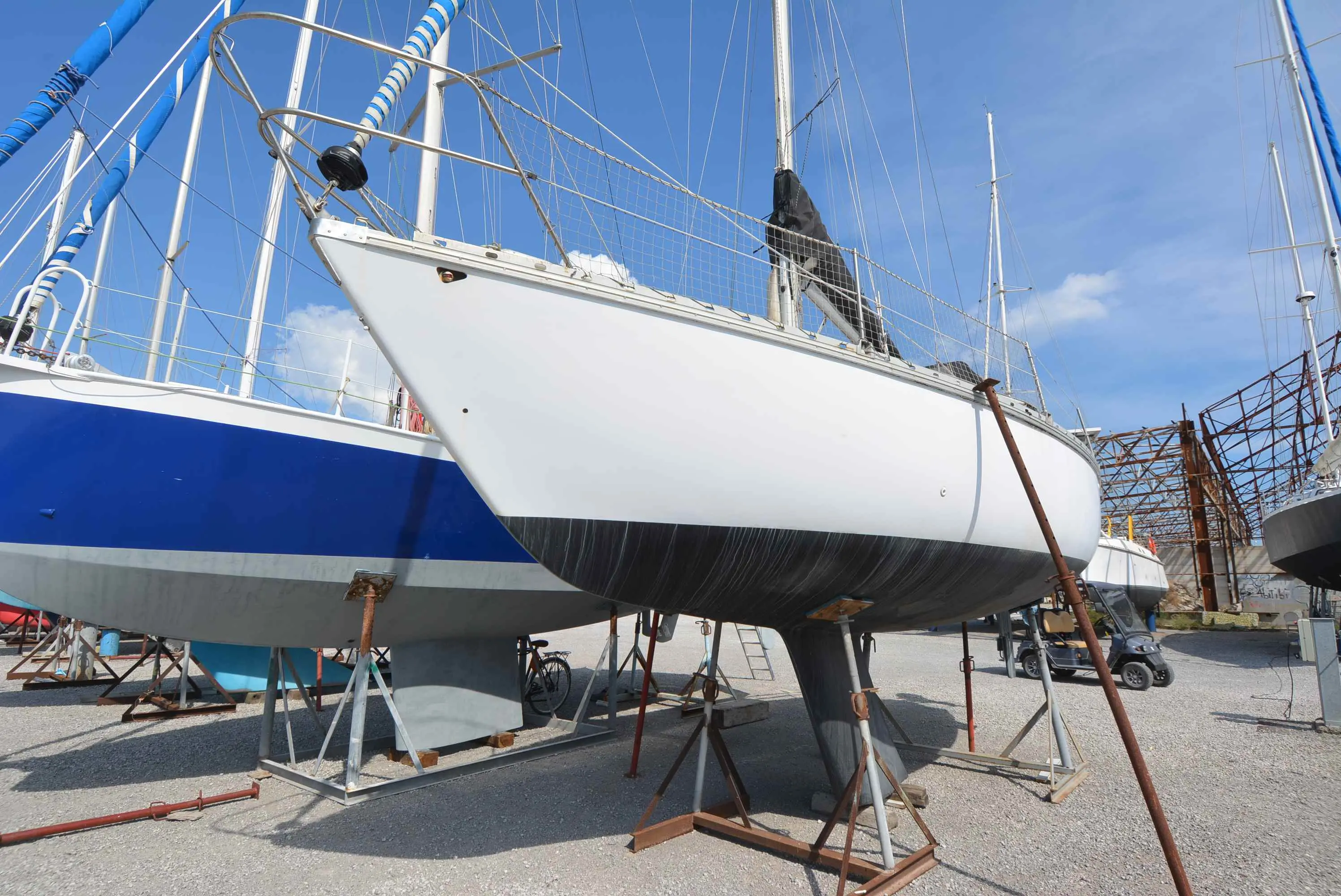 Jeanneau Brin de folie — Voilier blanc photographié à terre sur bers, entouré d'autres bateaux.
