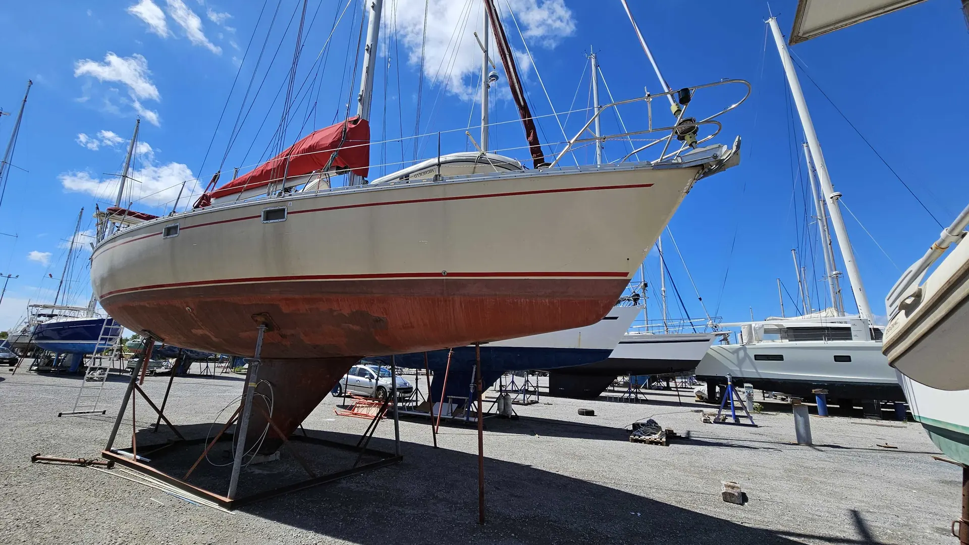 Jeanneau Sun Kiss 45 — Voilier blanc à liseré rouge posé sur bers dans un chantier naval.