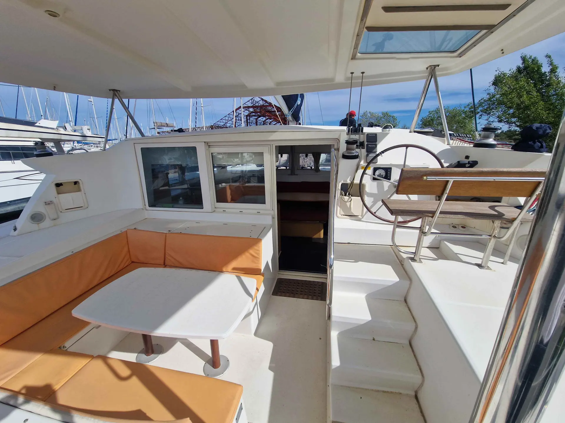 Lagoon 420 — Cockpit arrière couvert d’un catamaran, avec banquette, table et poste de barre.