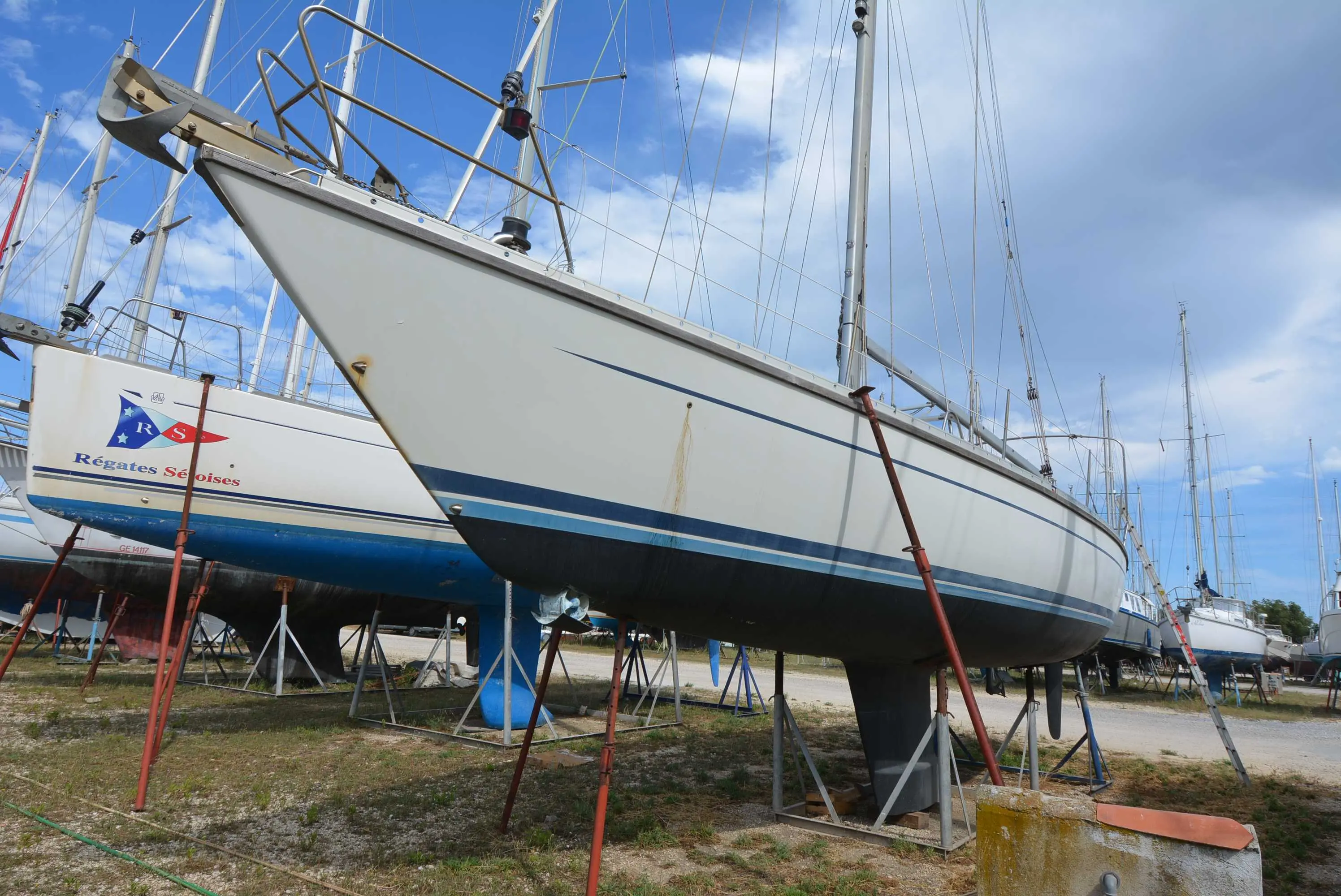 Luffe 46 — Voilier blanc et bleu photographié à terre, sur bers, dans un chantier nautique.