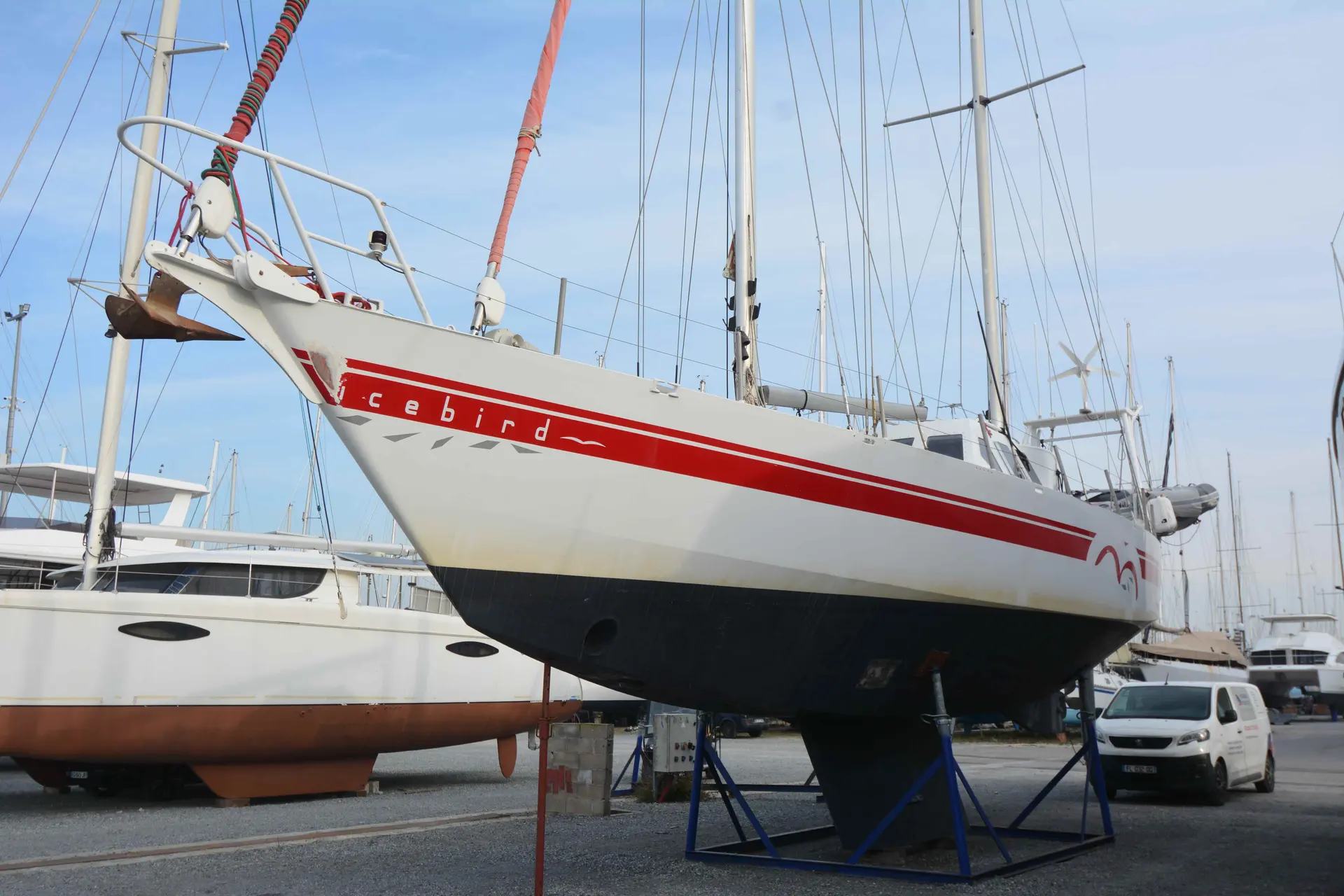 Meta Dalu 47 — Voilier blanc à bande rouge, photographié à terre dans un chantier naval.