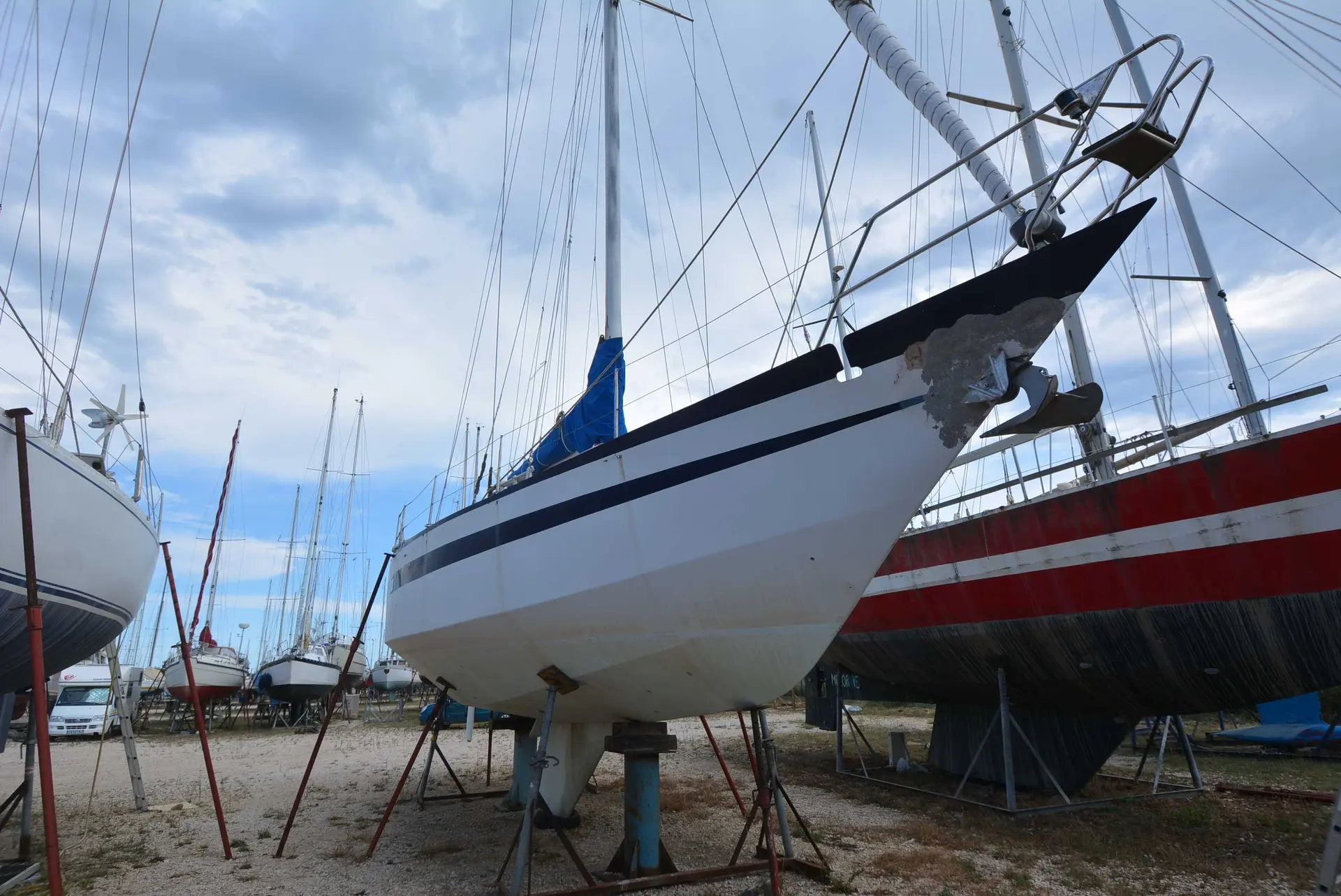 Amateur Reve Des Tropiques — Voilier blanc à liseré bleu, vu à terre sur bers dans un chantier naval.