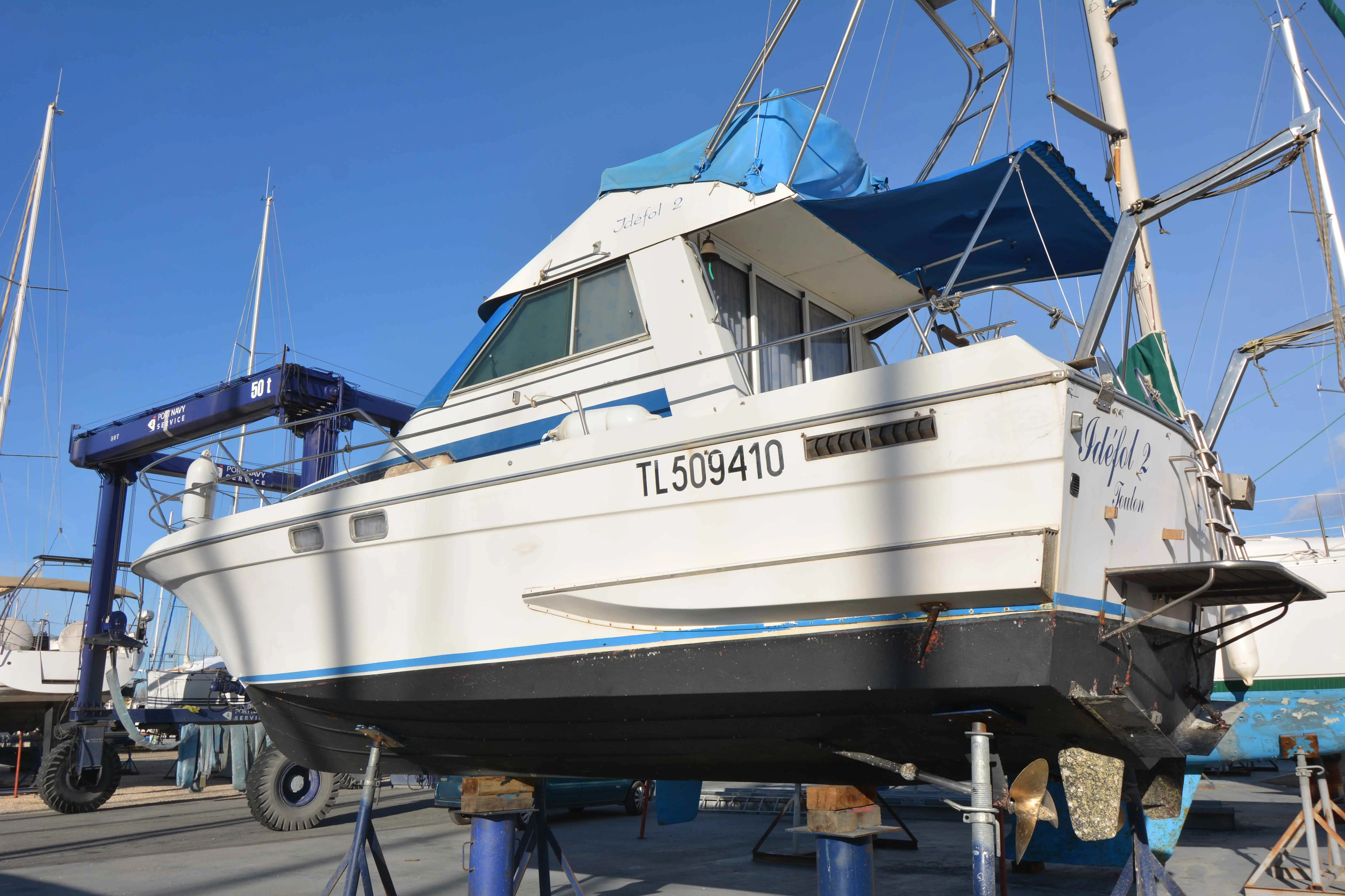 Yachting France Arcoa 970 — Vedette à moteur blanche et bleue photographiée à terre dans un chantier nautique.
