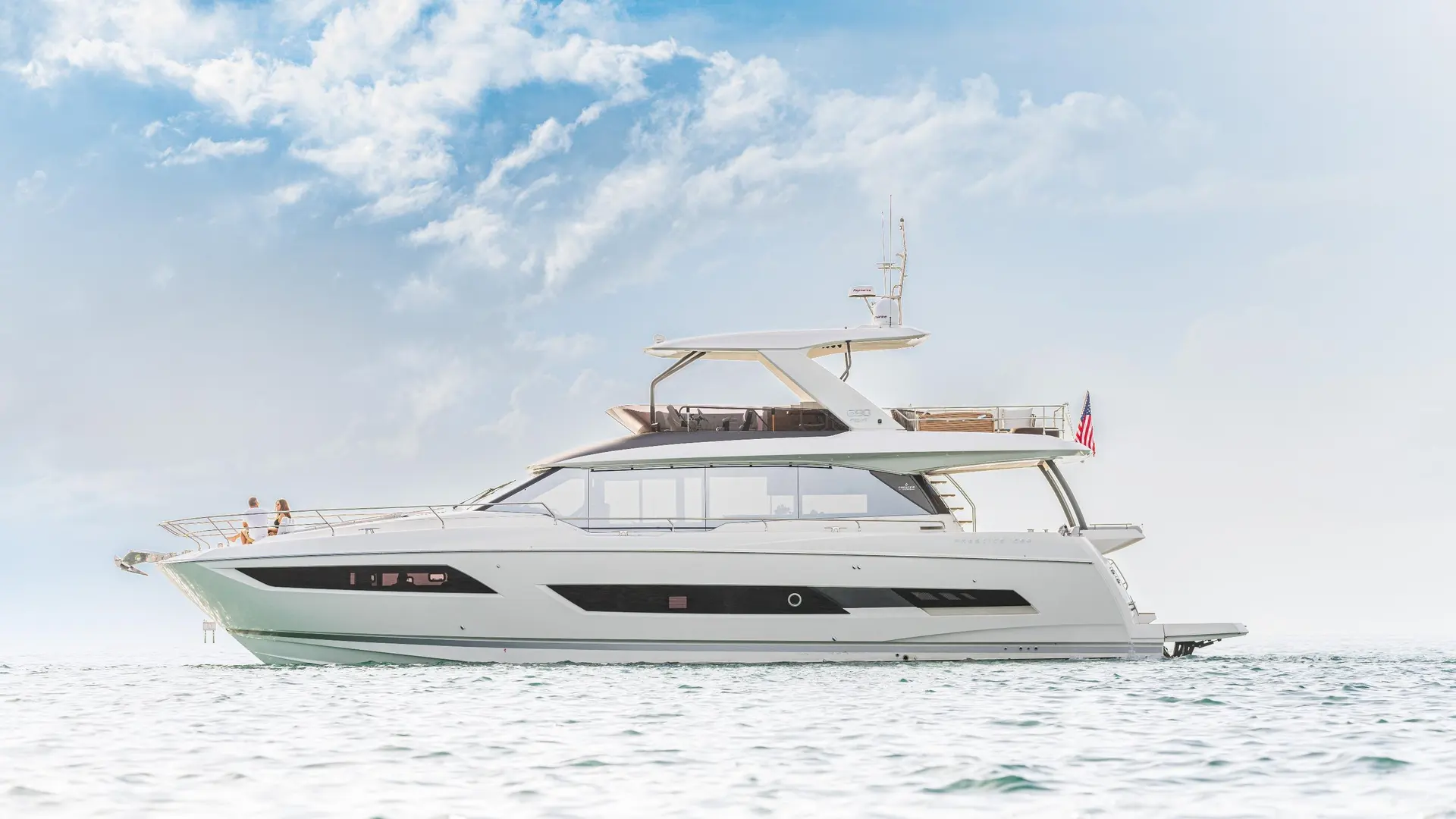 Prestige Yachts 690 — Yacht à moteur blanc photographié de profil sur une mer calme, sous un ciel nuageux.