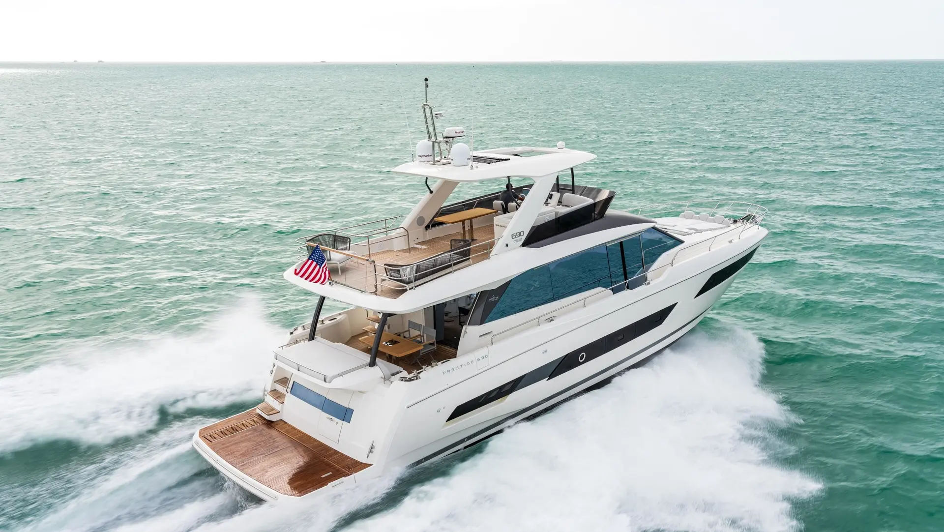 Prestige Yachts 690 — Bateau à moteur blanc vu de trois quarts arrière, en navigation sur la mer.