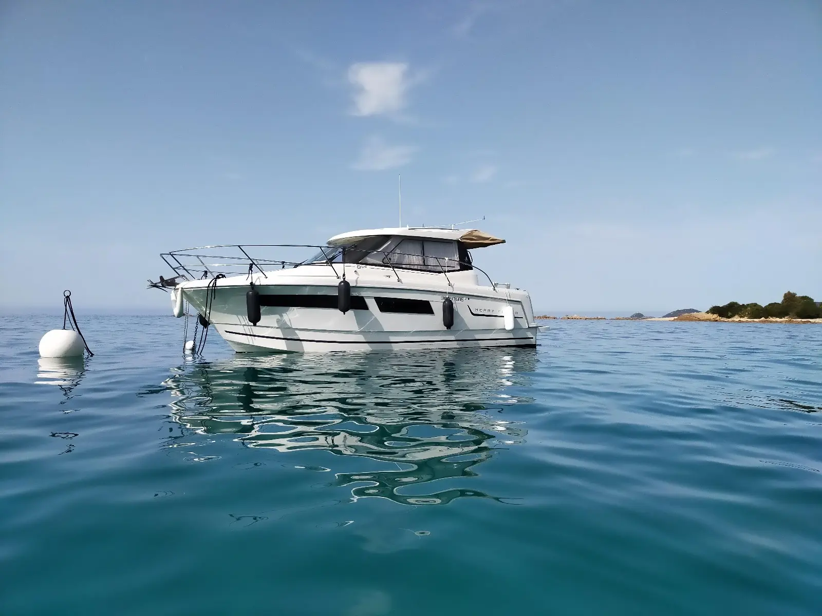 Jeanneau Merry Fisher — Bateau à moteur blanc vu de trois quarts au mouillage, en mer calme.