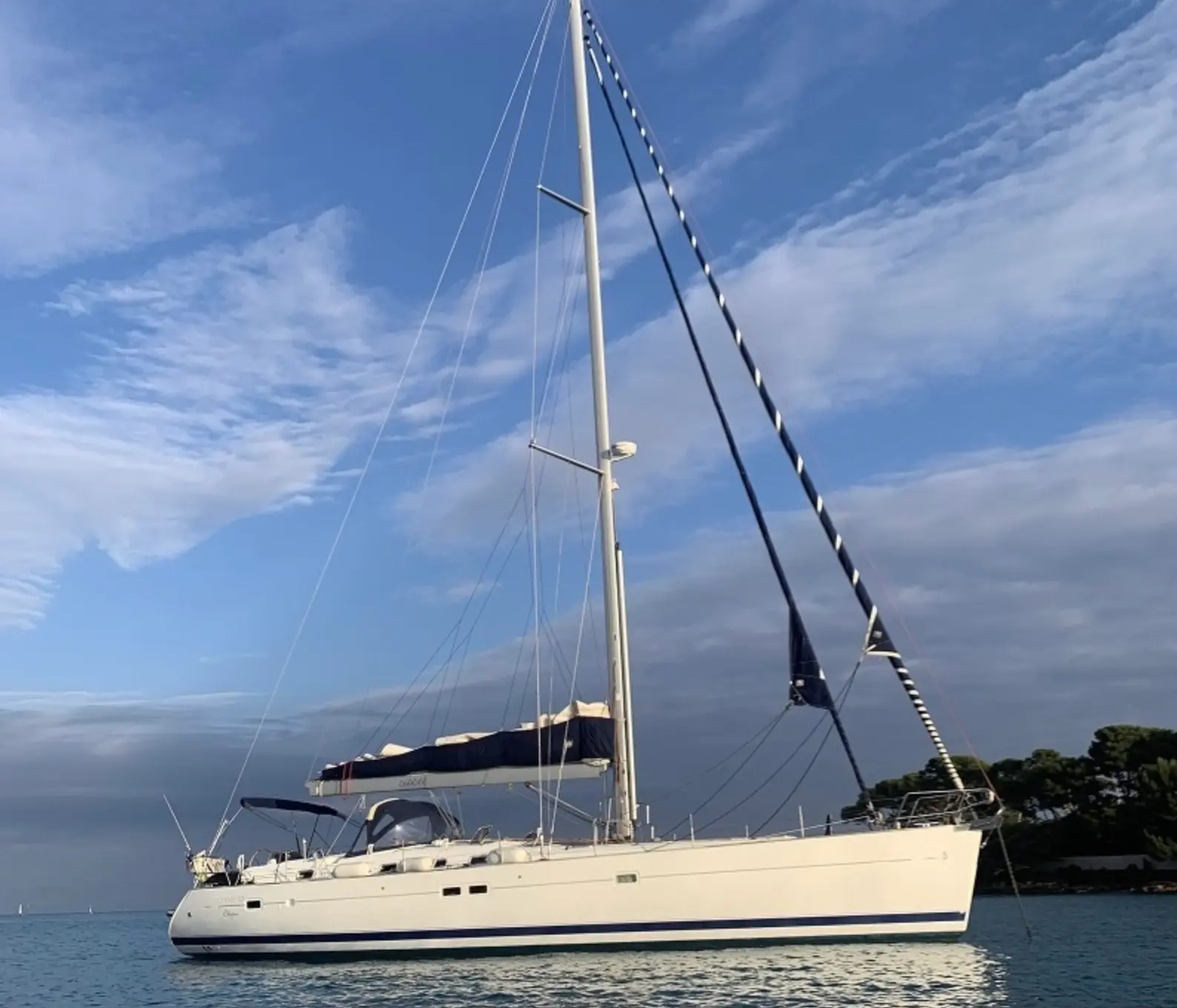 Beneteau Oceanis 523 — Voilier blanc vu de profil sur l’eau, avec son gréement et sa grand-voile ferlée.