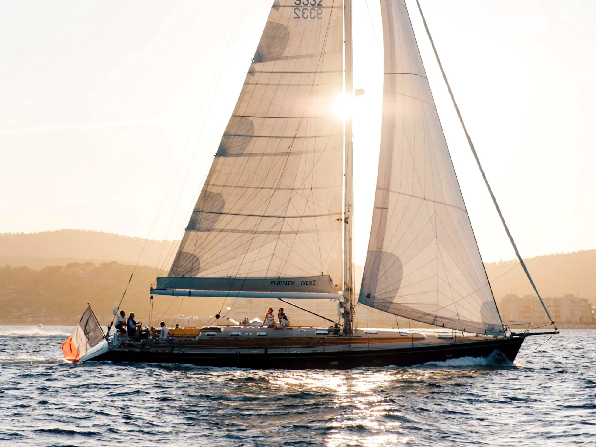 Custom Phenix Dixi — Voilier vu de profil, toutes voiles hissées, naviguant sur une mer ensoleillée.