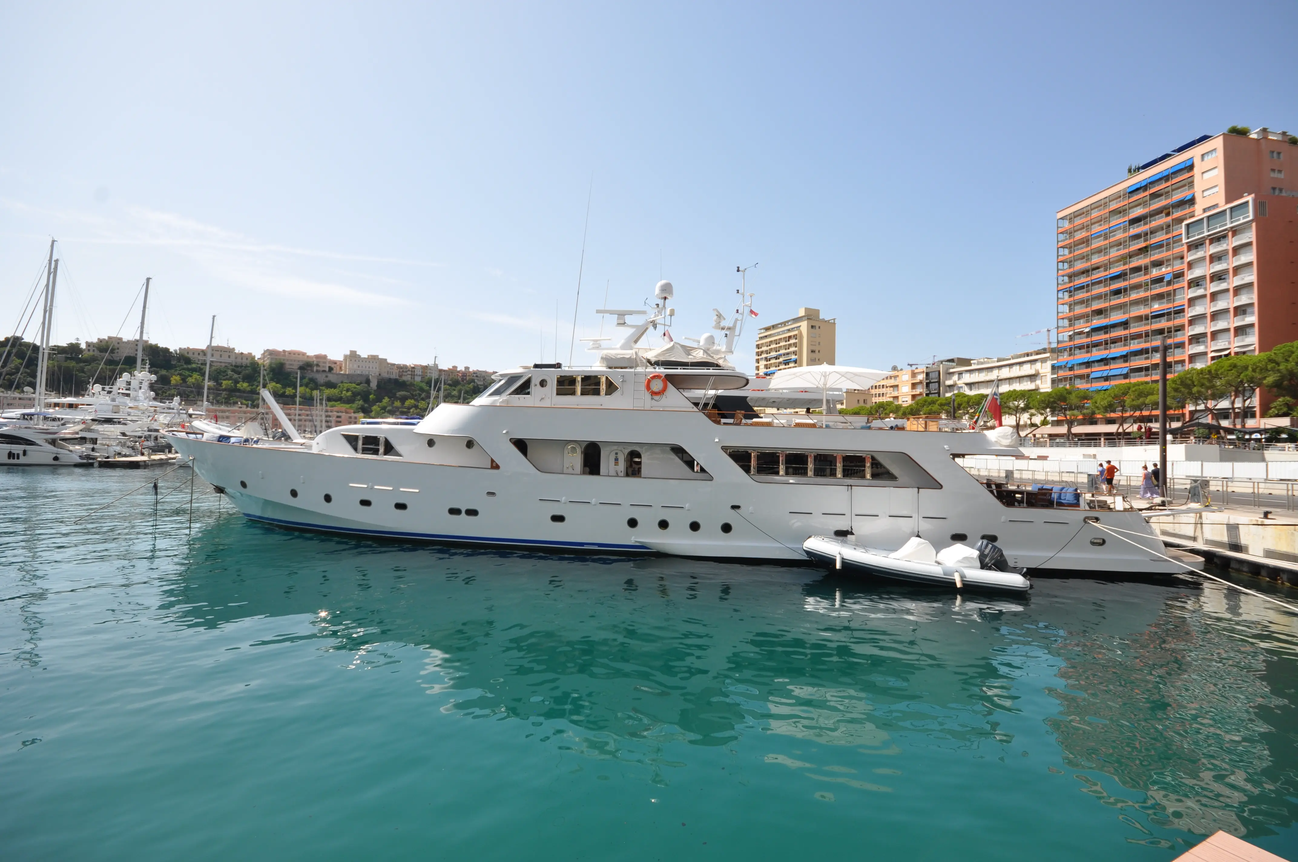 CRN 115 — Yacht blanc vu de profil, amarré dans un port urbain.
