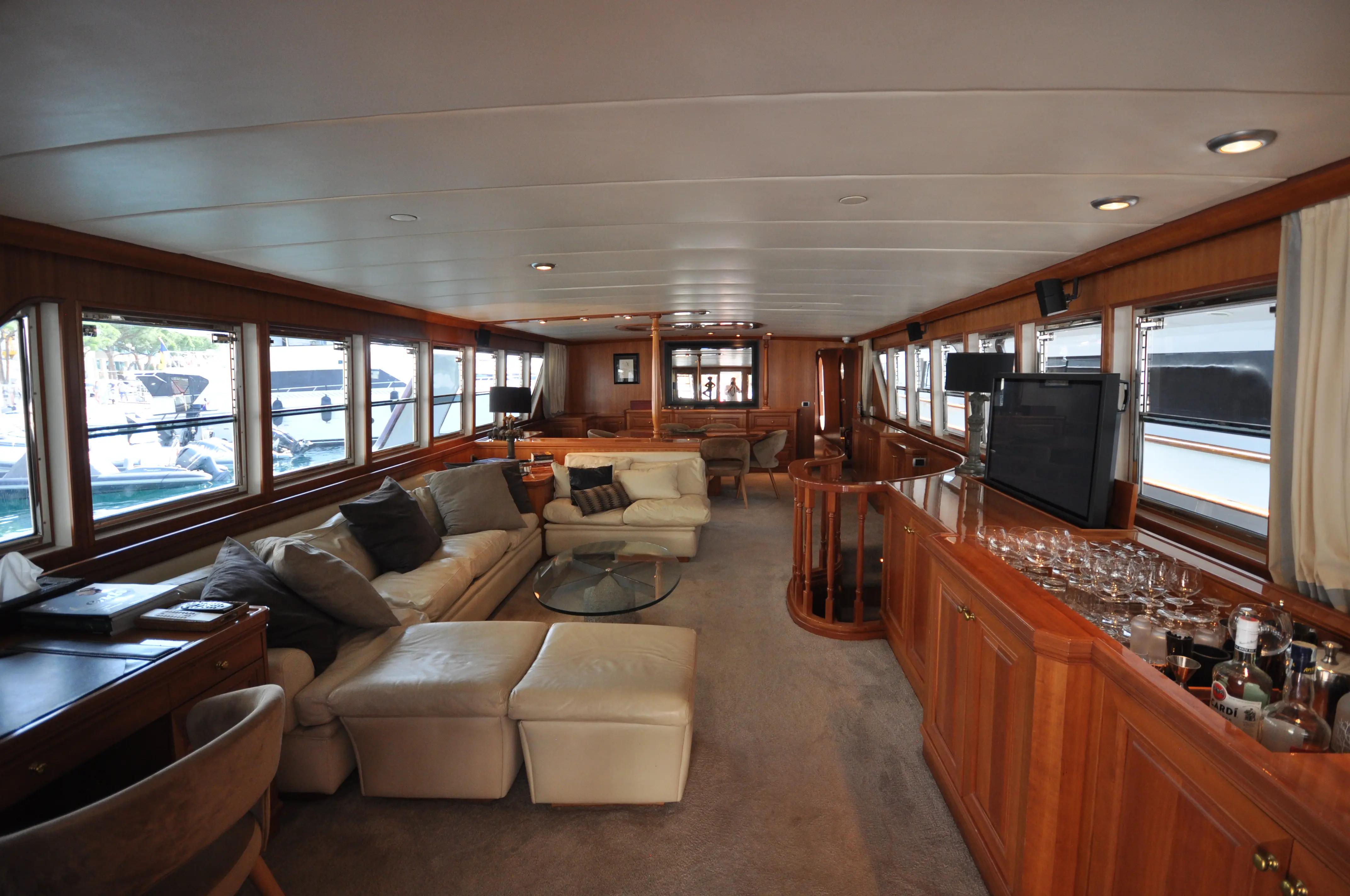 CRN 115 — Salon intérieur en bois avec sièges, bar et larges baies vitrées.